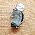 Crystal pendant with silver wire wrapping on a textured beige surface