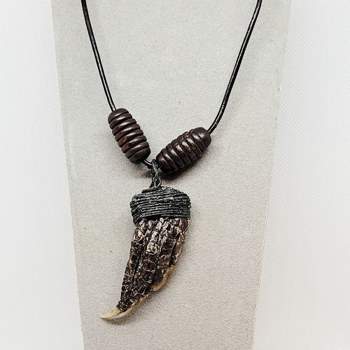 Necklace with an alligator paw pendant on a textured surface
