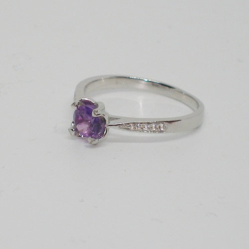 Silver ring with a purple gemstone on a white background