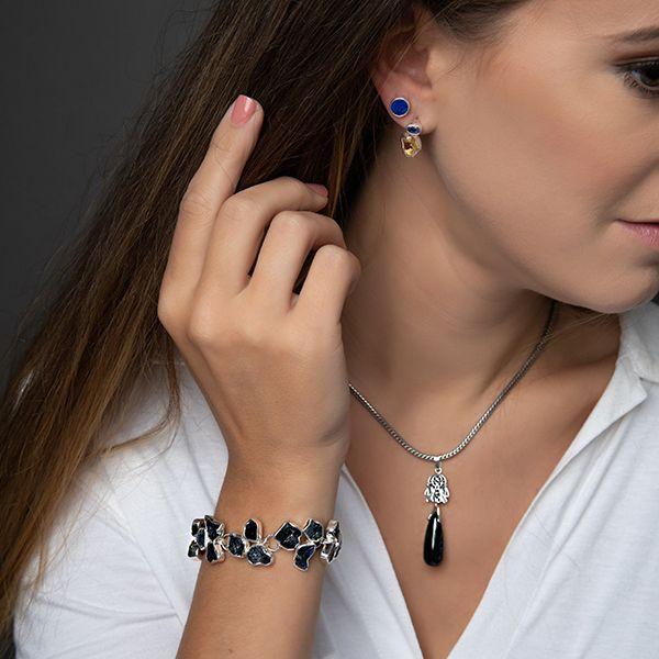 photo of a brunette model wearing a silver organic styled multi-gem raw blue sapphire bracelet with other jewelry