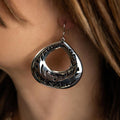 Photo of a brunette model wearing a silver dangle earring