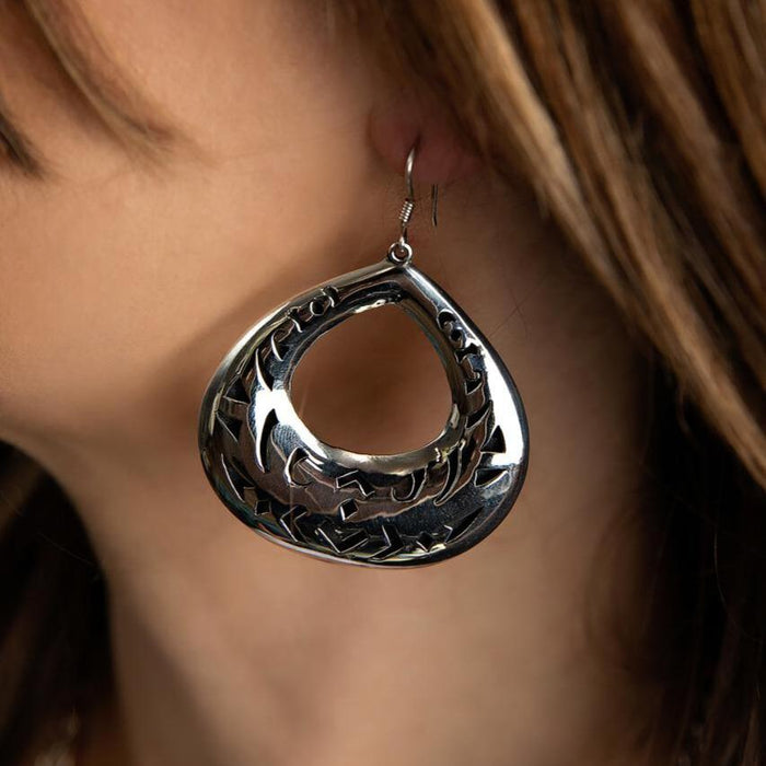 Photo of a brunette model wearing a silver dangle earring