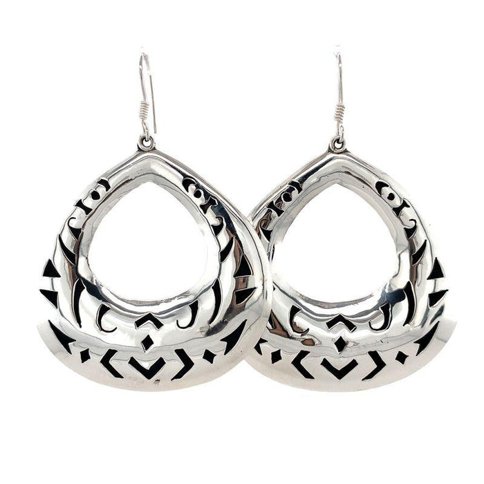 Photo of a pair of silver earrings with dark cut outs on a white back ground front view