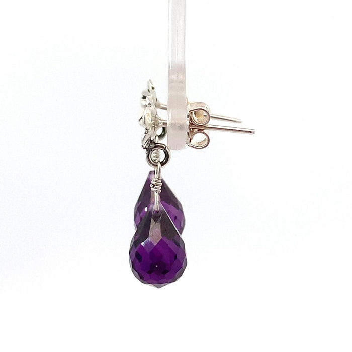photo of a pair of amethyst briolettes topped with a flower stud in silver suspended on a white background side view
