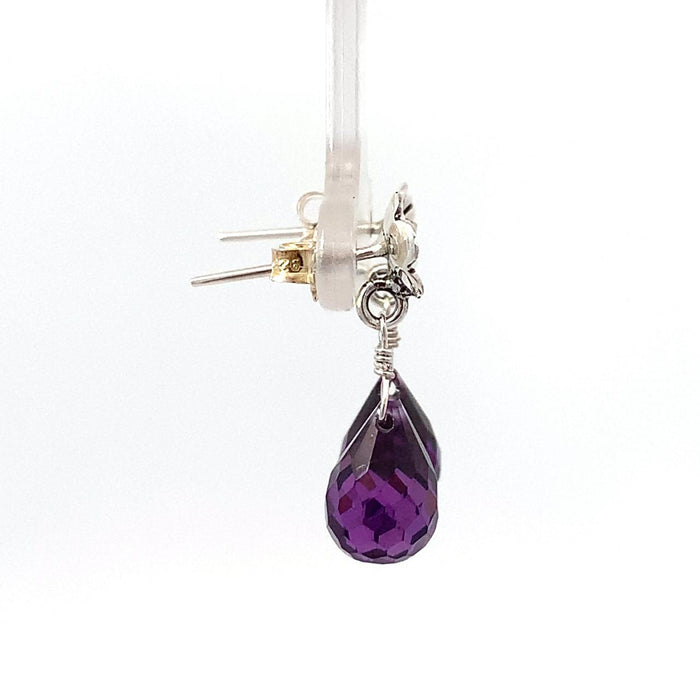 photo of a pair of amethyst briolettes topped with a flower stud in silver suspended on a white background side view