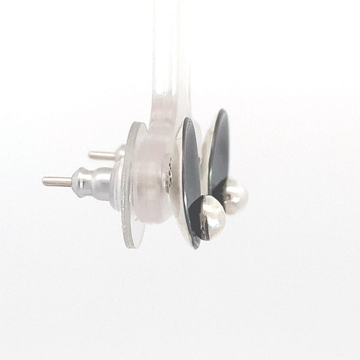 photo of a pair of black and silver circle shaped stud earrings on a white background side view