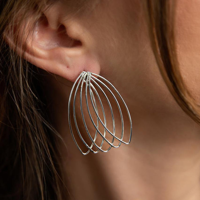 photo of a brunette model wearing a five-section silver fan-shaped earring