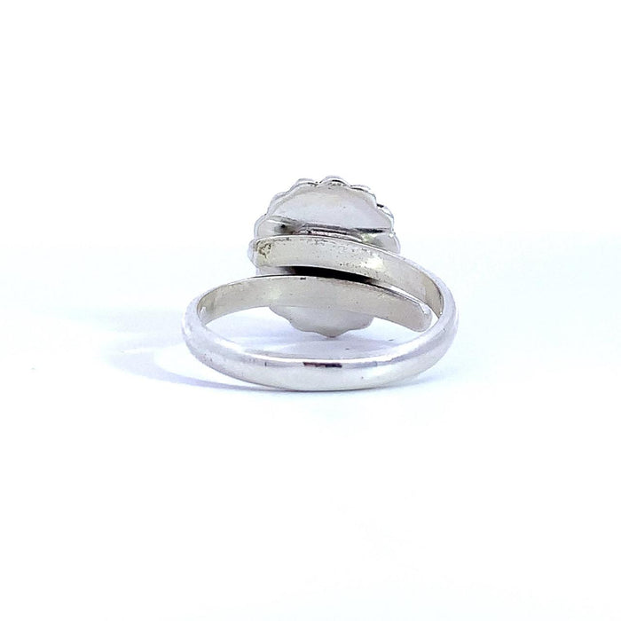 photo of a silver ring set with an oval blue gem finished with a beaded halo on a white background rear view