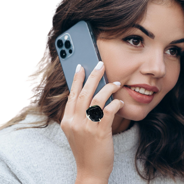 photo of a brunette model holding a cell phone and wearing a silver black geode ring on a white background