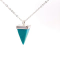 photo of a silver pendant set with a pyramid-shaped blue turquoise gem on a chain on a white background