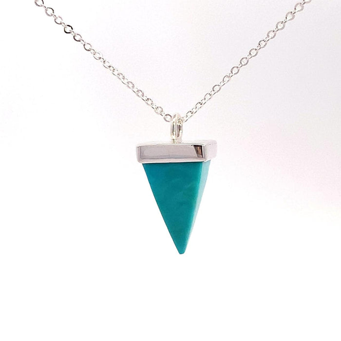 photo of a silver pendant set with a pyramid-shaped blue turquoise gem on a chain on a white background