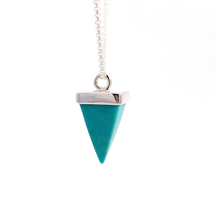 photo of a silver pendant set with a pyramid-shaped blue turquoise gem on a chain on a white background