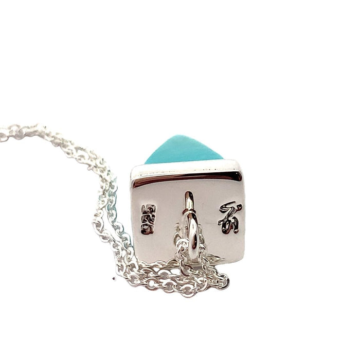 photo of a silver pendant set with a pyramid-shaped blue turquoise gem on a chain on a white background top view