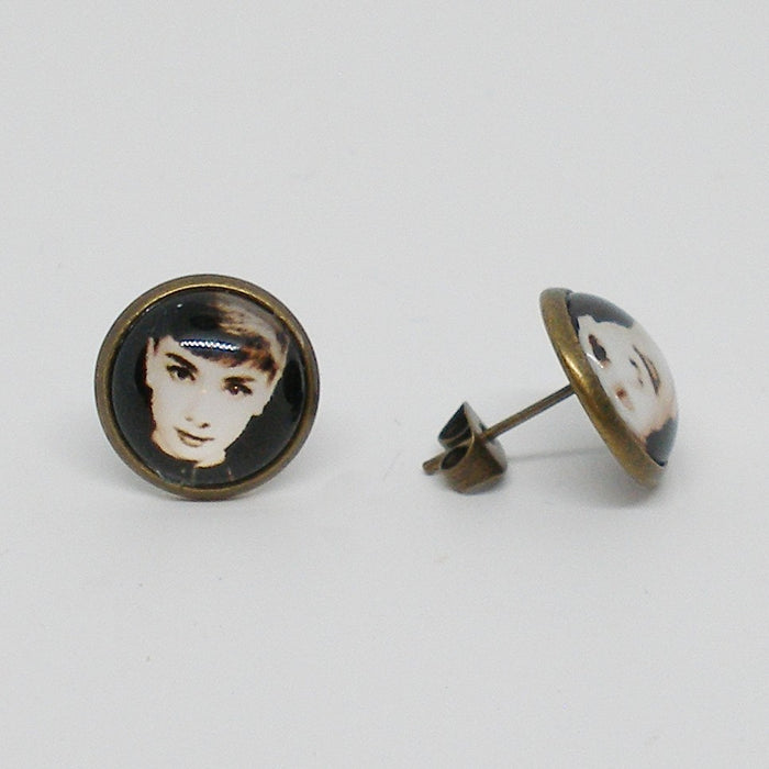 Pair of earrings with portrait designs on a light gray background