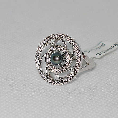 Silver ring with a central black pearl and diamond accents on a gray background