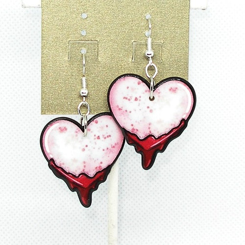 Heart-shaped earrings with red dripping design on a gold card.