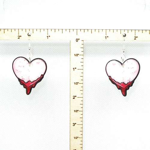 Heart-shaped earrings with a red dripping design on a white background with a ruler for scale.