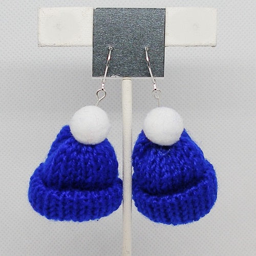 Blue knitted earrings with white pom pom tops on a gray background