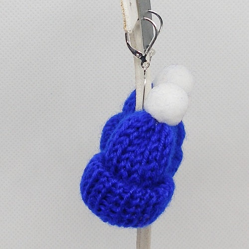 Blue knitted ski hat earrings with a white pom-pom on a gray background