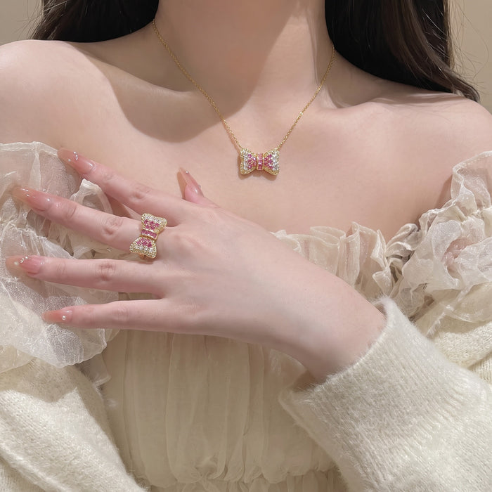 Cute, sparkling, and beautifully feminine, the Blush Bow Set is made for someone who loves soft romantic jewelry with a playful luxe touch. Designed with a crystal-studded bow necklace and matching ring, this set brings a sweet pink glow that feels perfect for everyday styling, special moments, or thoughtful gifting.