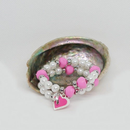 Pink and white beaded bracelet with a heart charm inside a shell on a light gray background