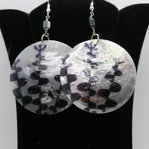 Round earrings with black and white pattern on a black stand.