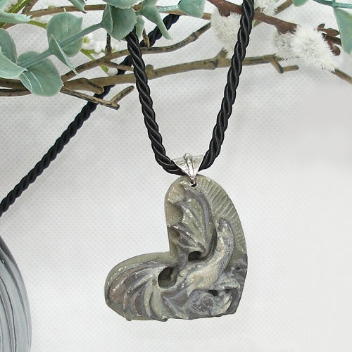Necklace with a carved heart-shaped stone pendant on a white background