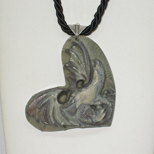 Decorative pendant on a black cord against a white background