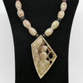 Necklace with beads and a decorative pendant on a black stand.