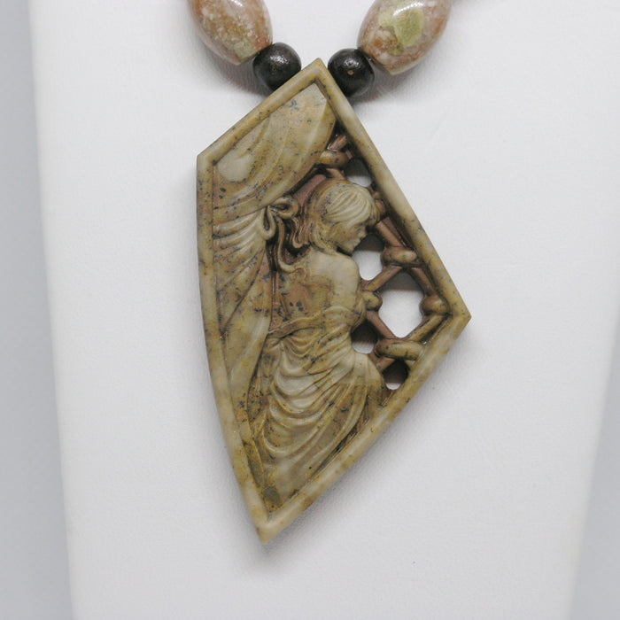 Carved stone pendant with a figure on a white background
