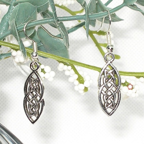Silver celtic knot earrings on a branch with leaves and flowers