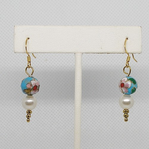 Pair of earrings with floral design beads on a white display stand against a light gray background