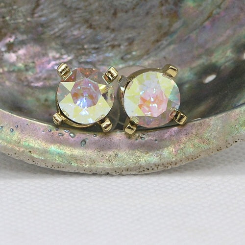 Pair of gold earrings with iridescent crystals on a shell background