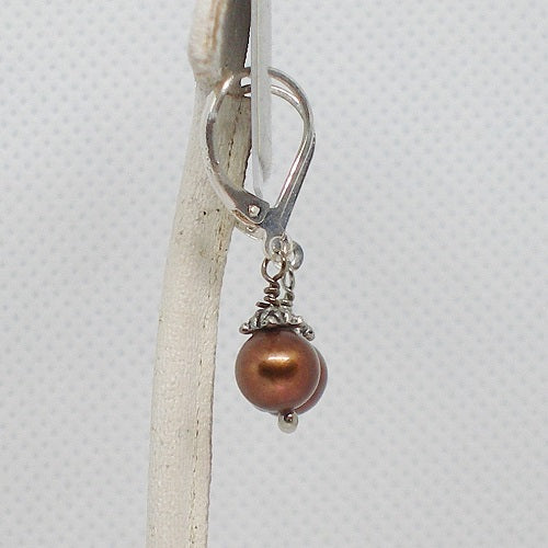 Silver earring with a brown pearl on a white background