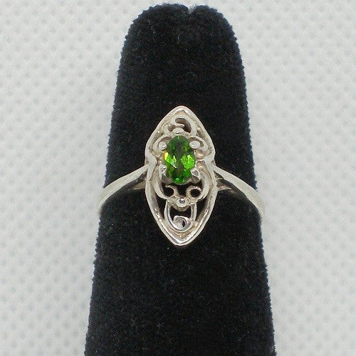 Silver ring with a green gemstone on a black velvet stand against a gray background