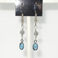 Silver earrings with light blue stones on a white background