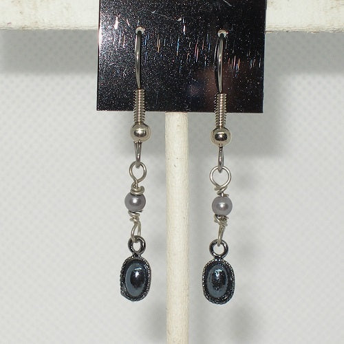 Pair of silver earrings with black stones on a white background