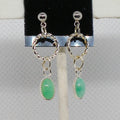 Silver earrings with green stones on a display stand.