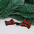 Red and green striped hair bows on black clips with a Christmas tree branch in the background