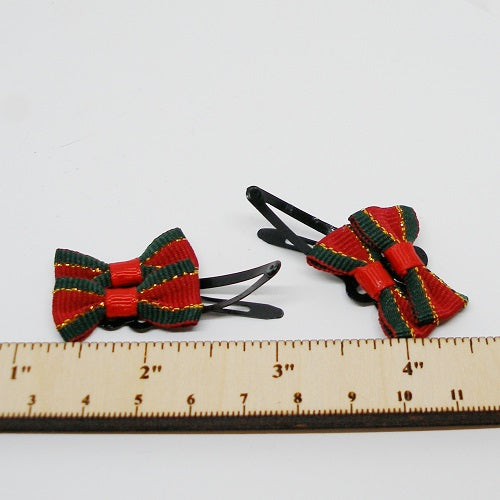 Red and green bow hair clips with black hairpins on a white background, measured against a ruler.