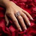 photo of a models hand wearing a silver six stone garnet ring on a bed of rose petals