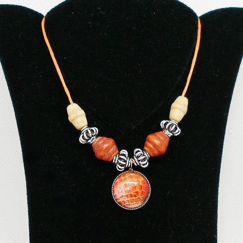 Necklace with orange and beige beads on a black stand