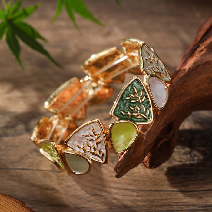 Artistic, colorful, and inspired by botanical details, the Enamel Leaf Bangle combines sculptural leaf motifs with glossy colored panels and warm gold-tone outlines. Its mix of triangular shapes, organic leaf detailing, and jewel-like shades creates a bold vintage-inspired look, while the elastic construction makes it easy and comfortable to slip on for everyday or occasion wear.