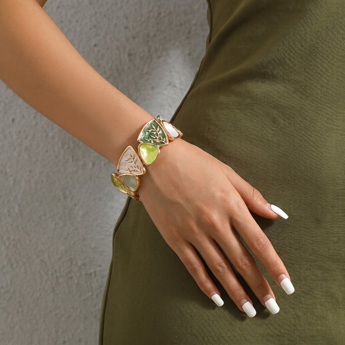 Artistic, colorful, and inspired by botanical details, the Enamel Leaf Bangle combines sculptural leaf motifs with glossy colored panels and warm gold-tone outlines. Its mix of triangular shapes, organic leaf detailing, and jewel-like shades creates a bold vintage-inspired look, while the elastic construction makes it easy and comfortable to slip on for everyday or occasion wear.
