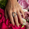 photo of a model wearing a silver horse bit themed ring  on a bed of flower petals