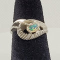Silver ring with an opal stone on a black stand