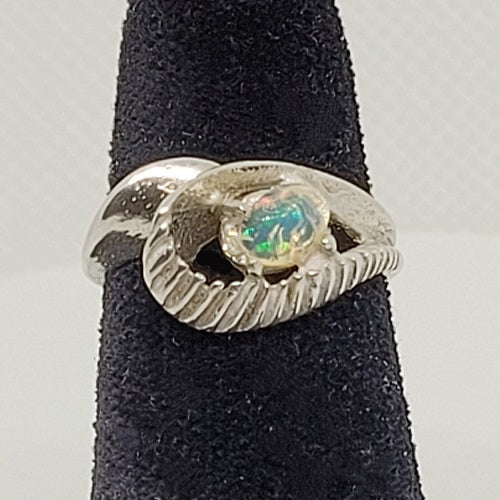 Silver ring with an opal stone on a black stand