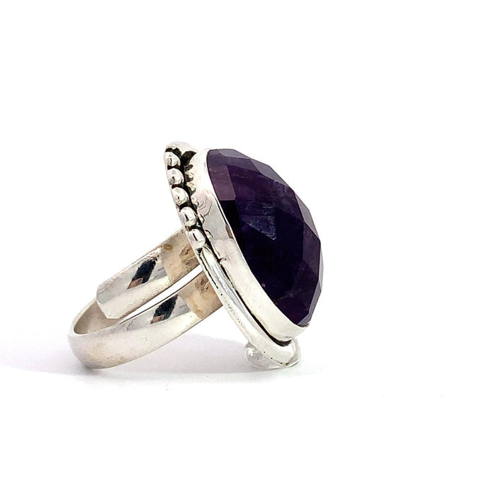 photo of a silver faceted oval amethyst ring with dots details in the frame on a white background side view