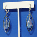 Silver earrings with clear crystals on a white stand against a blue background