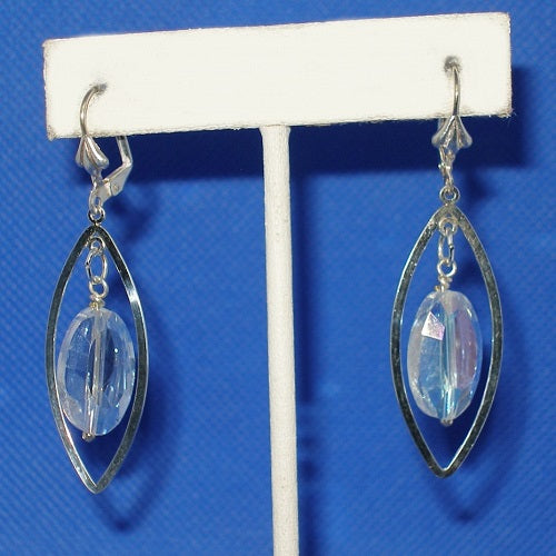 Silver earrings with clear crystals on a white stand against a blue background
